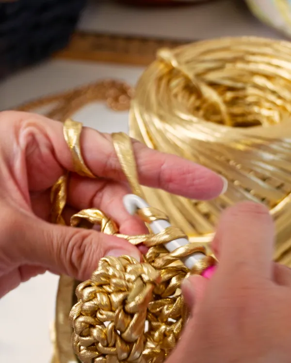 Manos tejiendo hilo dorado para un bolso de Morain Atelier.