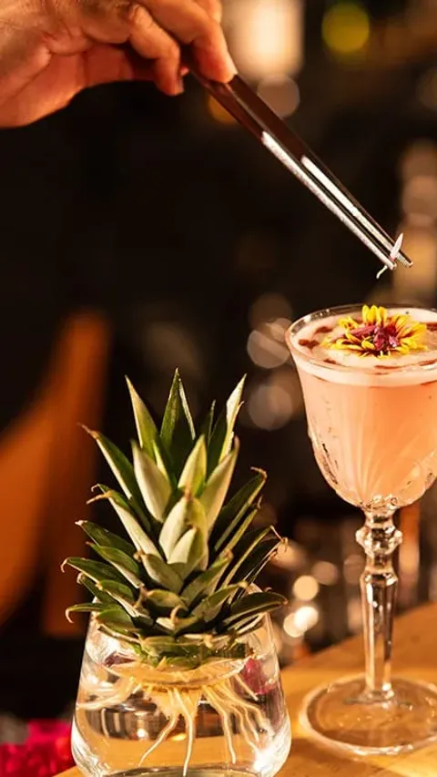 Un bartender decora un coctel rosa en Karuma.